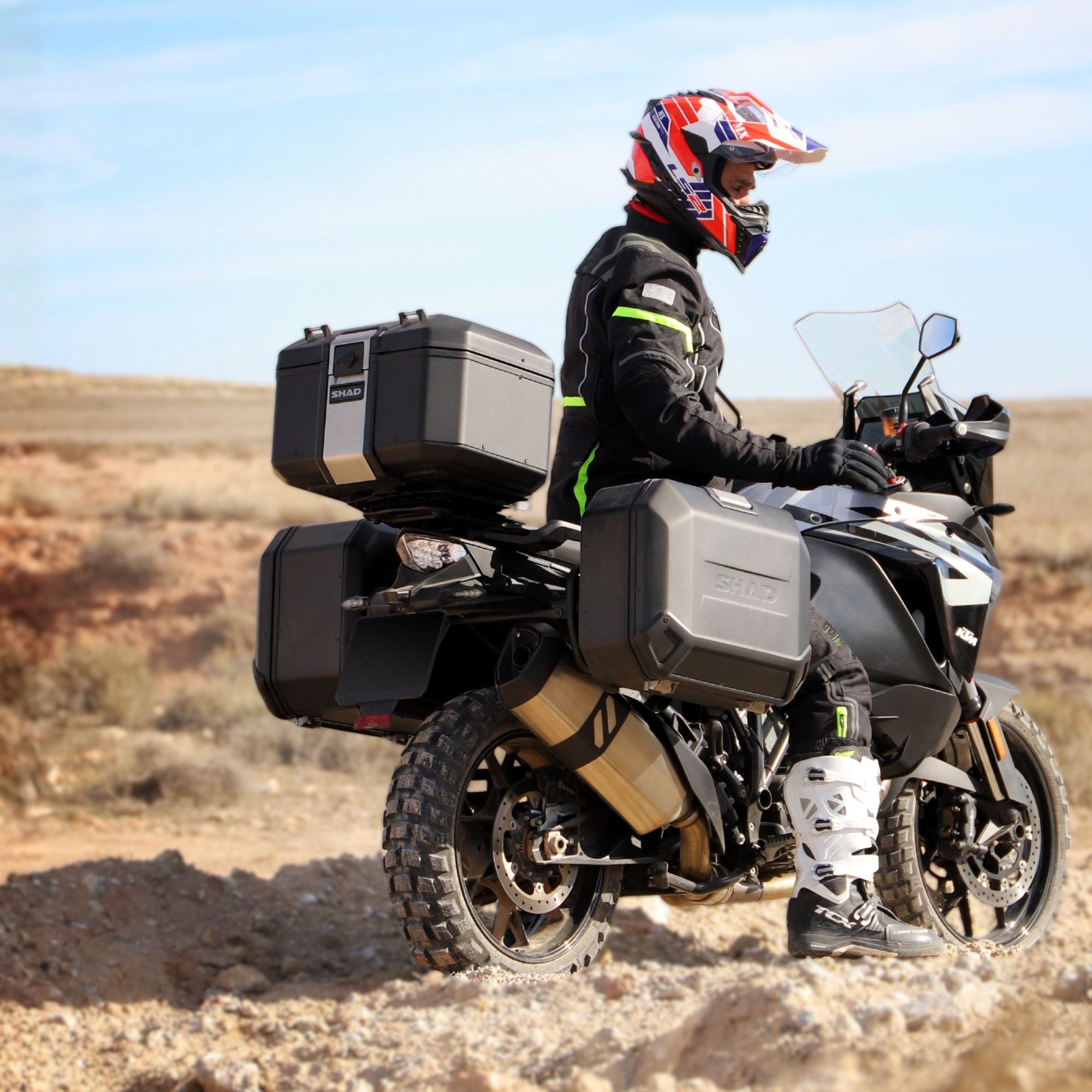 motorcyclist on a motorcycle with SHAD top box and panniers luggage in adventure desert setting